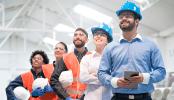 Trabalhadores felizes em uma indústria com equipamentos de segurança olhando para cima.